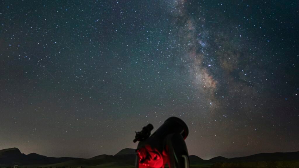 Télescope sur trépied dans un champ sous un ciel nocturne étoilé